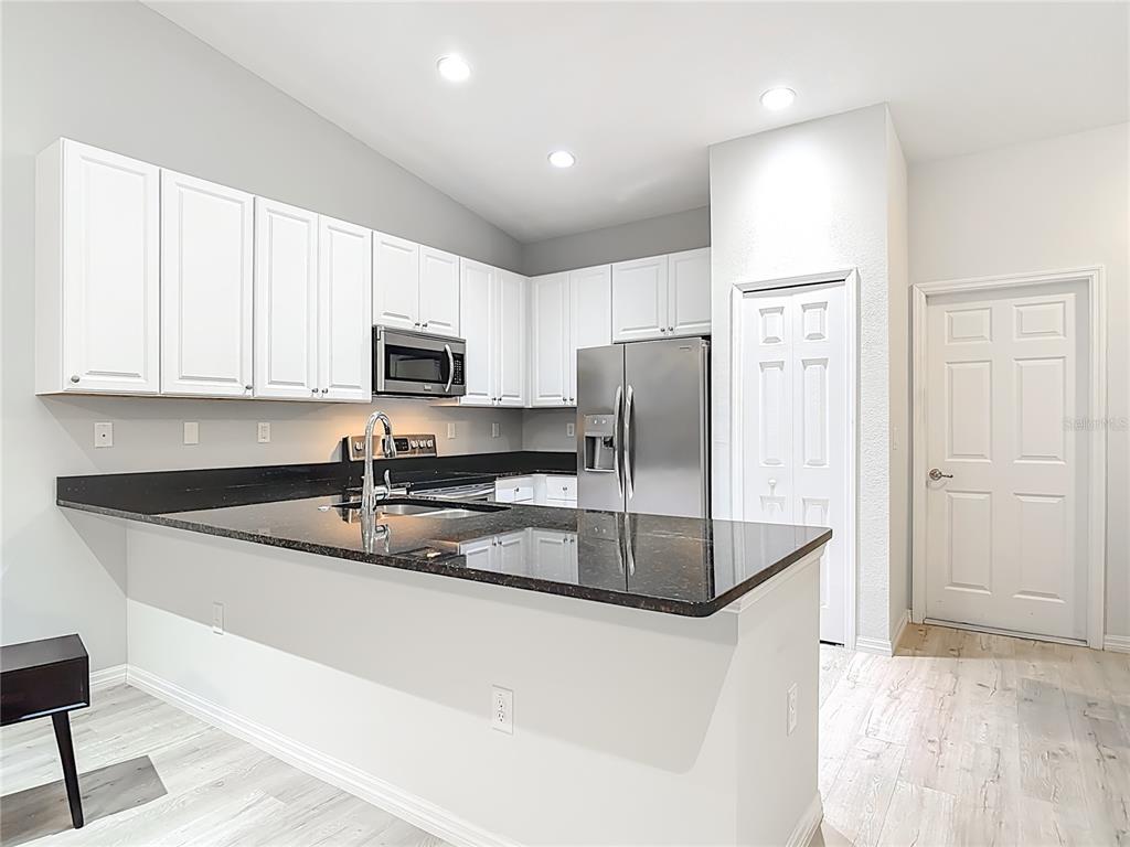 202 Walter Stevens Way DeLand, FL 32724 - Photo 12 of 34 a kitchen with stainless steel appliances granite countertop a sink a stove a refrigerator a microwave and cabinets