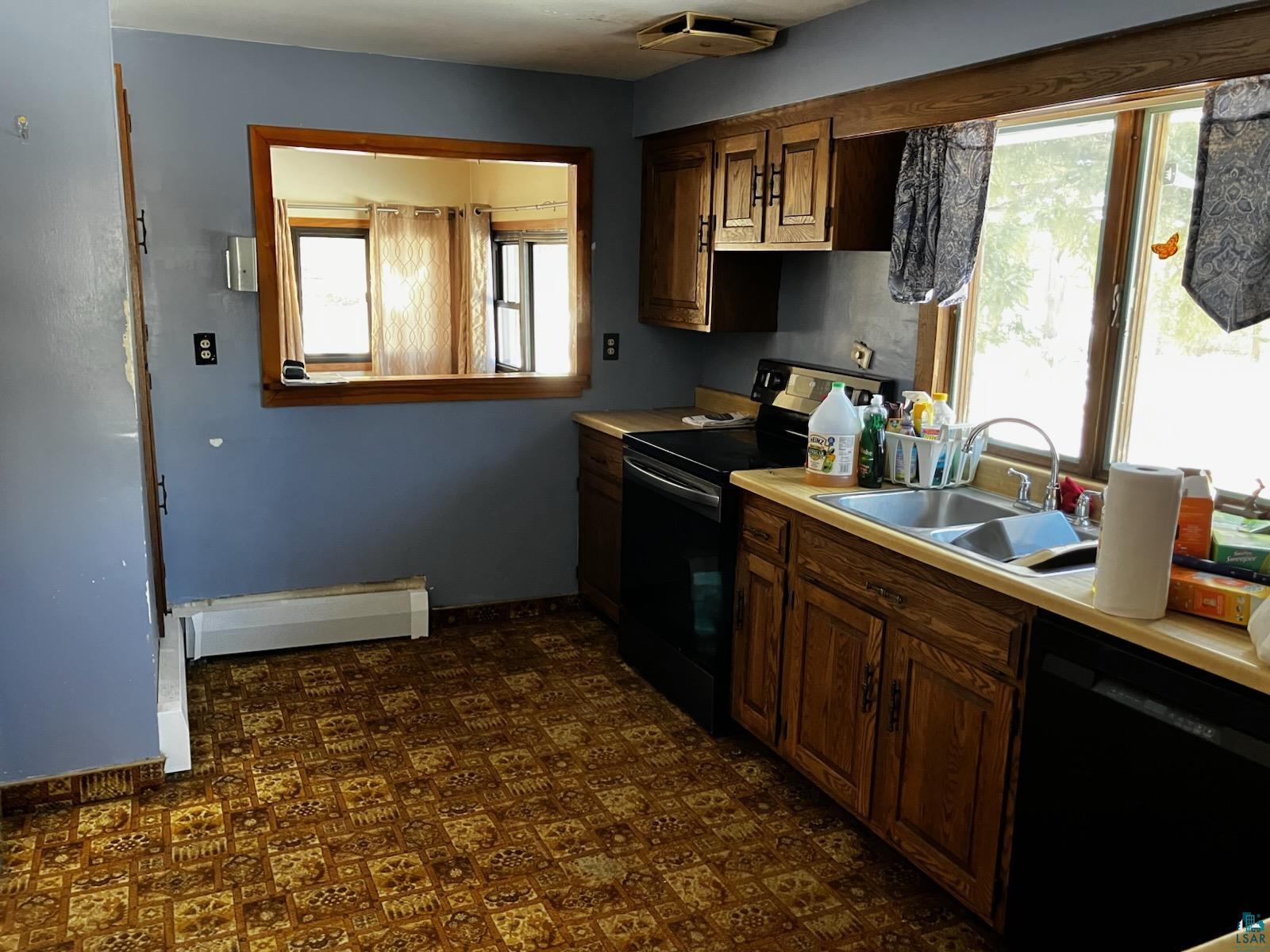8372 Garden Street Kerrick, MN 55756 - Photo 5 of 24 Kitchen featuring black appliances, a healthy amount of sunlight, a baseboard heating unit, and a sink