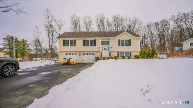 a front view of a house with a yard covered with snow and trees