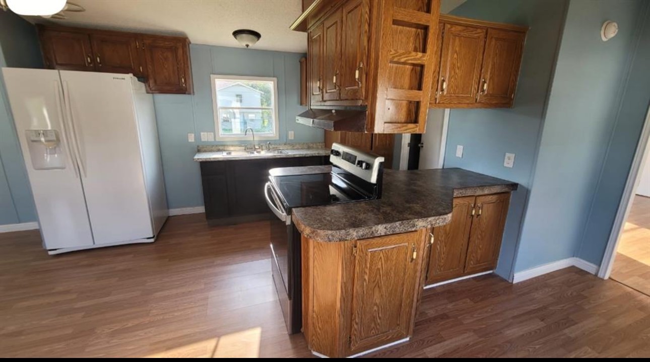 1403 Old Greens Road Houston, TX 77032 - Photo 15 of 19 a kitchen with granite countertop a refrigerator a sink a stove and wooden floor
