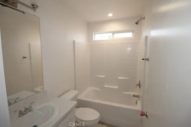 a bathroom with a bathtub shower sink vanity and toilet