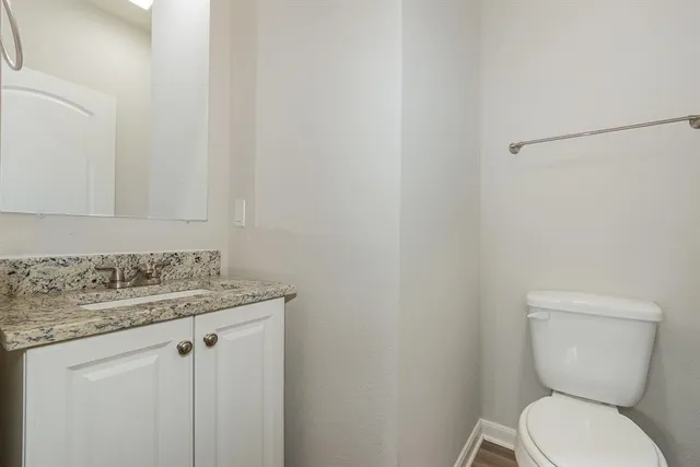 a bathroom with a granite countertop toilet and a sink