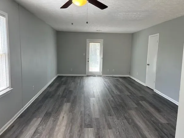 an empty room with wooden floor and windows