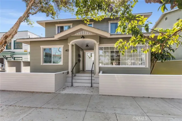 a view of a white house with large windows and a small yard