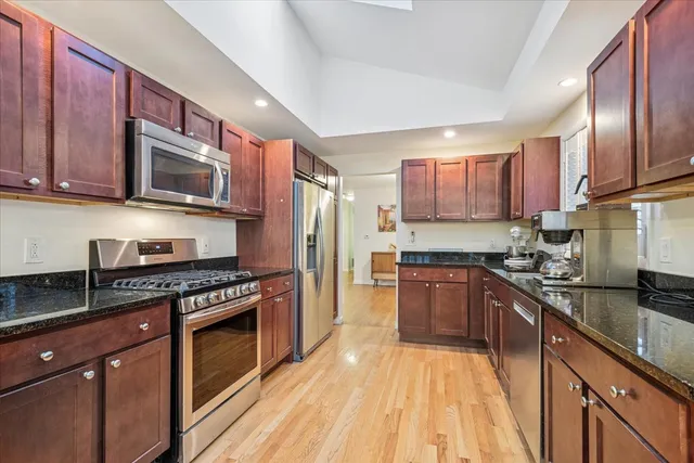 a kitchen with granite countertop wooden cabinets stainless steel appliances and a sink