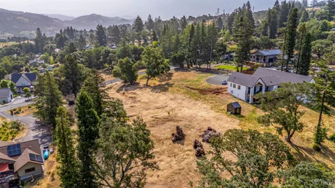an aerial view of a houses with a yard and mountain view in back