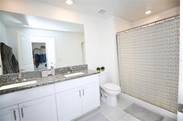 a bathroom with a granite countertop toilet a sink and a mirror