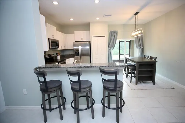 a kitchen with stainless steel appliances granite countertop a sink stove refrigerator and cabinets