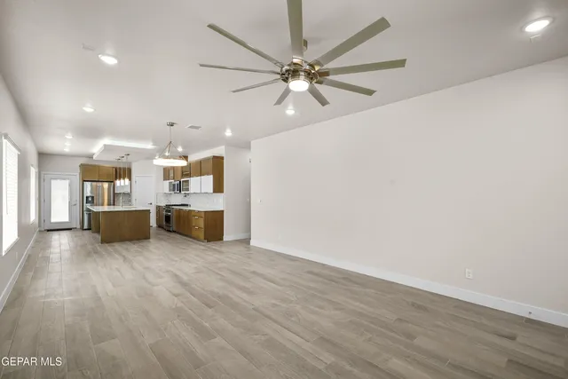a view of a livingroom with a fireplace a ceiling fan and wooden floor