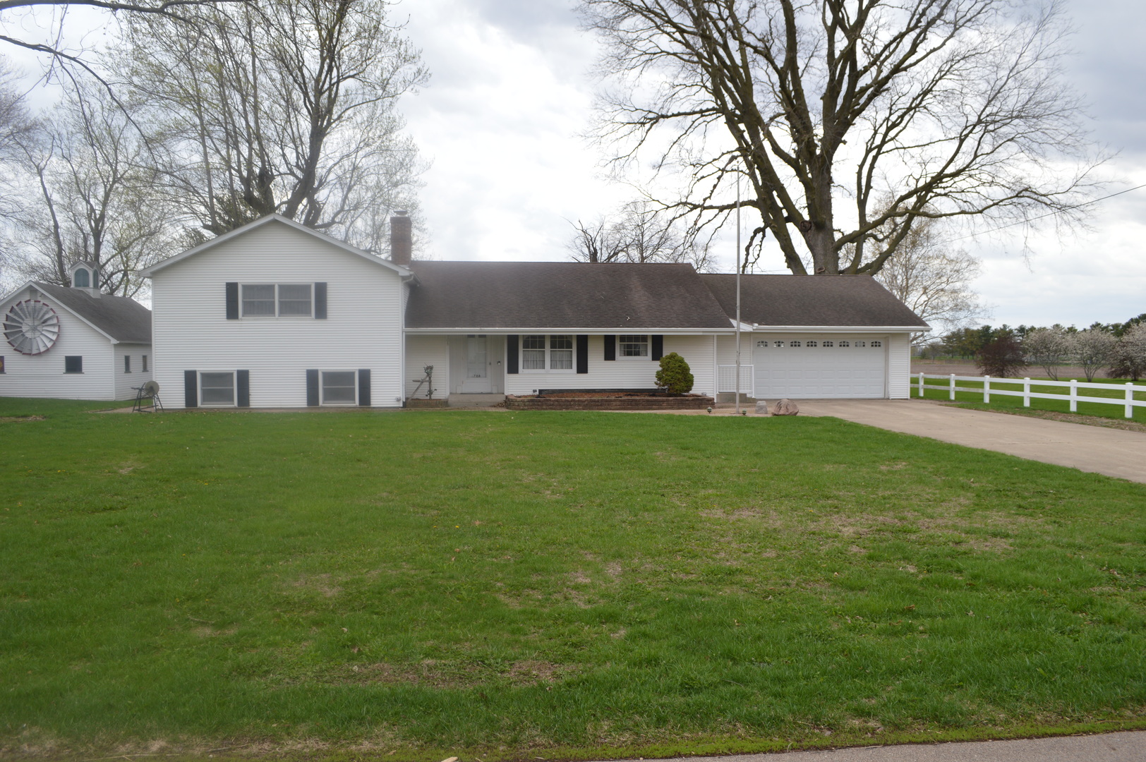 a view of house with a big yard and large trees