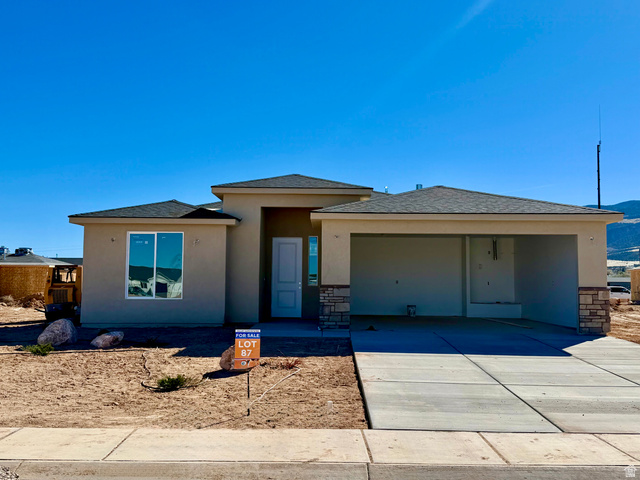 4956 North 925 East, Unit 87 Enoch, UT 84721 - Photo 1 of 12 Prairie-style house featuring stucco siding, an attached garage, driveway, and stone siding