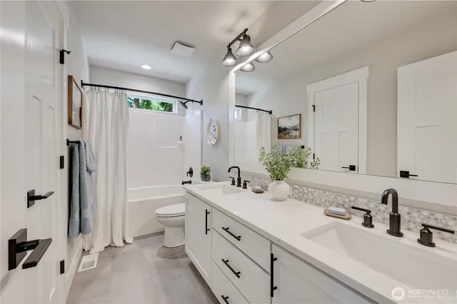 a bathroom with a double vanity sink toilet mirror and shower