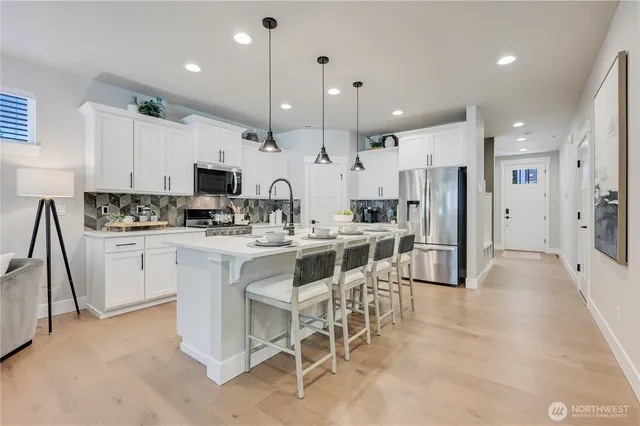 a kitchen with kitchen island white cabinets and stainless steel appliances
