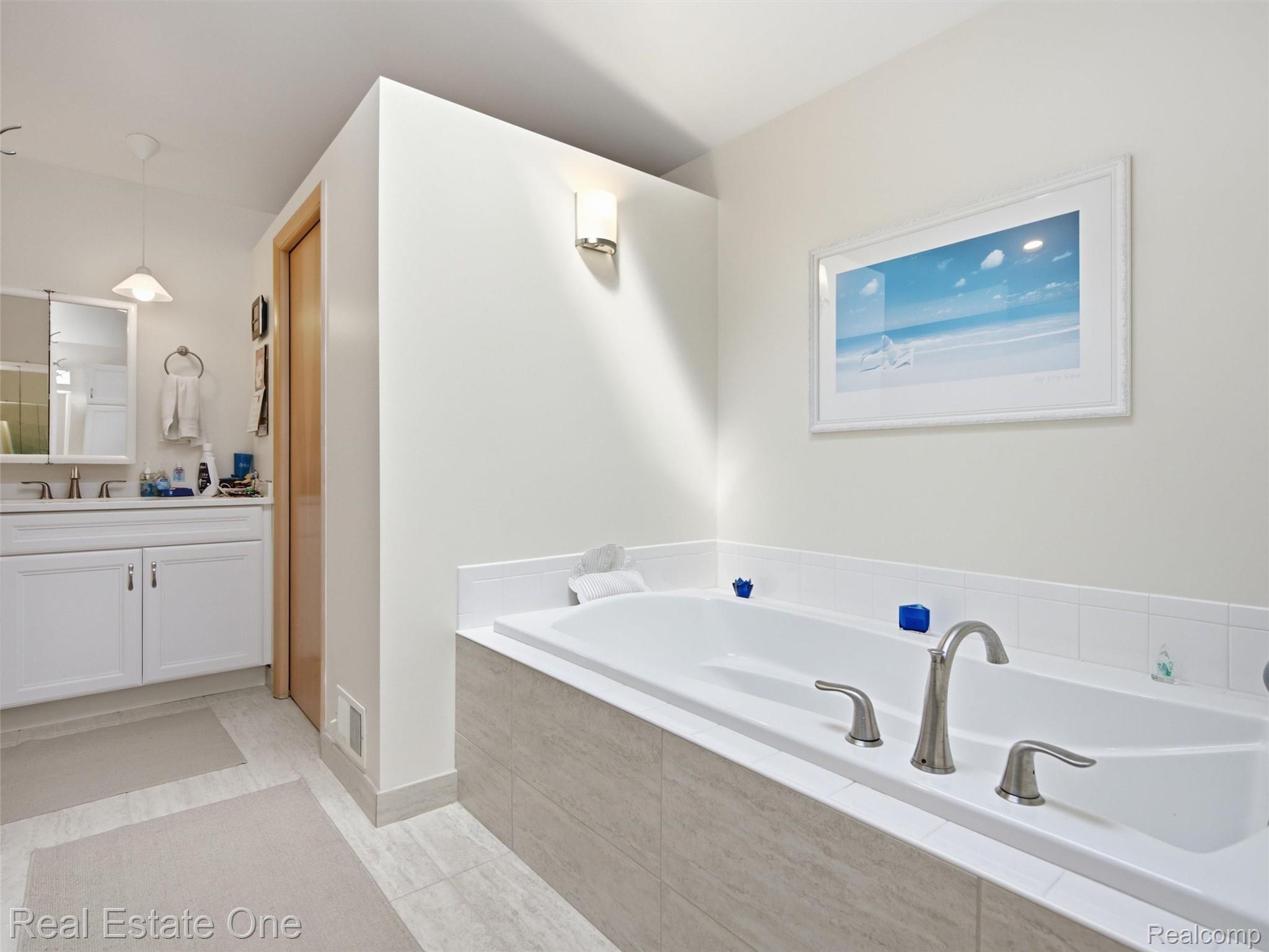 2626 West Wattles Road Troy, MI 48098 - Photo 30 of 65 Built-in soaking tub with brushed nickel fixtures, white tile surround, and light-toned tile-front paneling