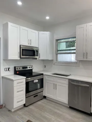 a kitchen with white cabinets stainless steel appliances and sink