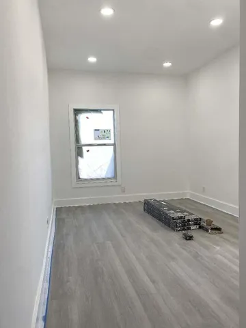 an empty room with wooden floor and window