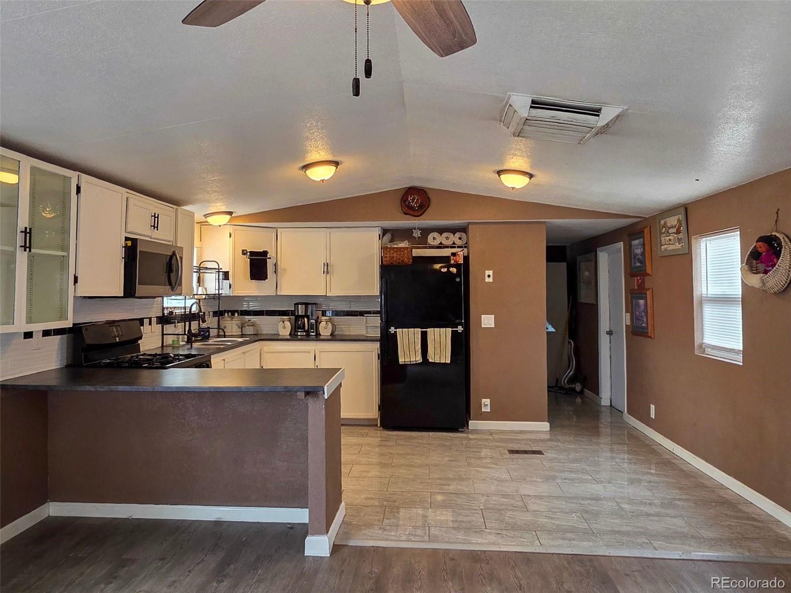 1401 9th Street Fort Lupton, CO 80621 - Photo 5 of 17 a large kitchen with stainless steel appliances kitchen island granite countertop a refrigerator a stove top oven a sink dishwasher and white cabinets
