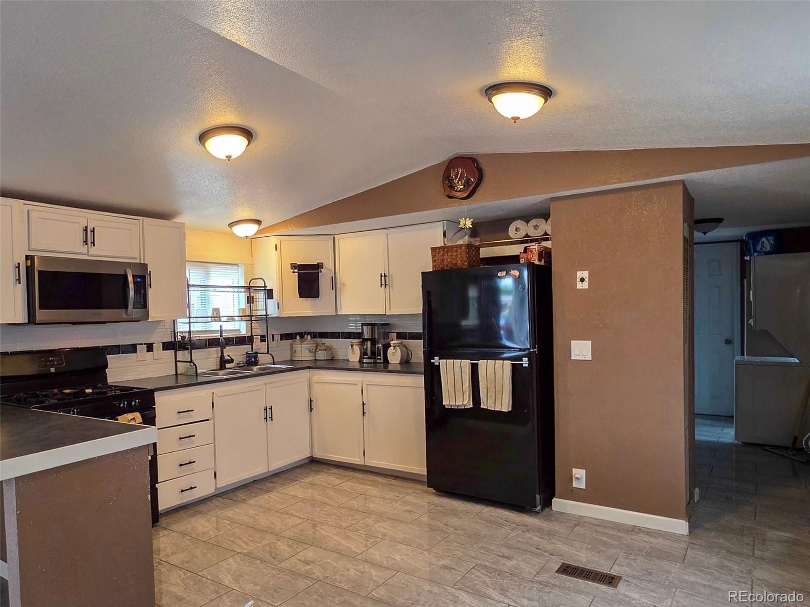 1401 9th Street Fort Lupton, CO 80621 - Photo 6 of 17 a kitchen with granite countertop a refrigerator and a sink