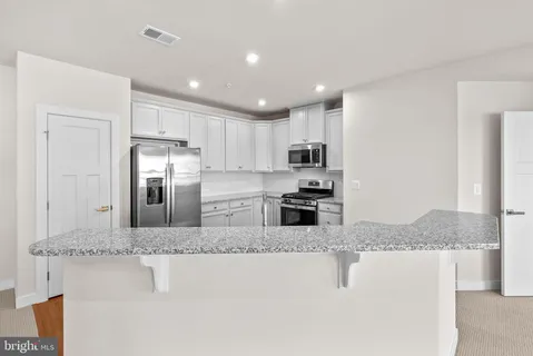 a kitchen with stainless steel appliances granite countertop a refrigerator sink and stove