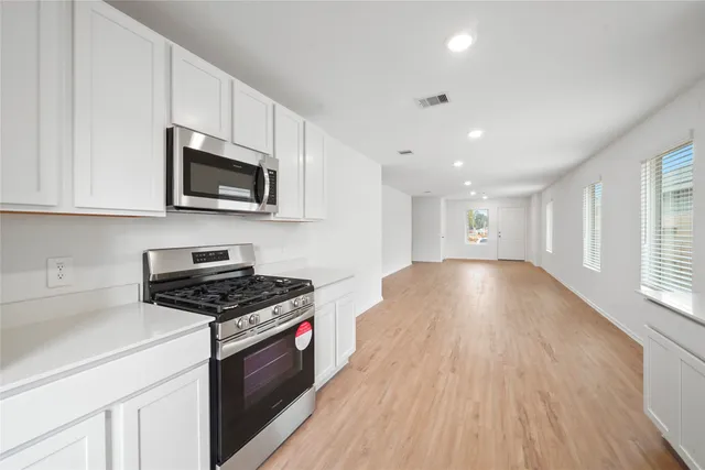 a kitchen with stainless steel appliances a stove a microwave and white cabinets