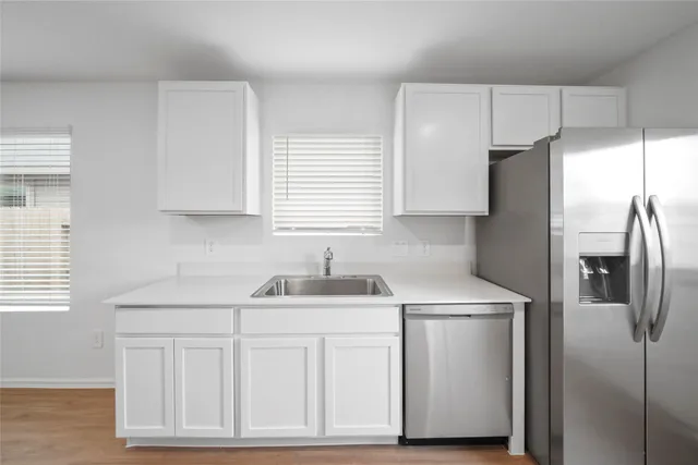 a kitchen with white cabinets and refrigerator