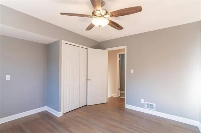 an empty room with wooden floor fan and windows
