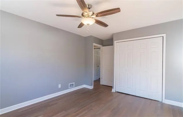 an empty room with wooden floor and ceiling fan