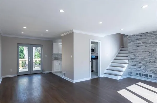 a view of an empty room with wooden floor and stairs