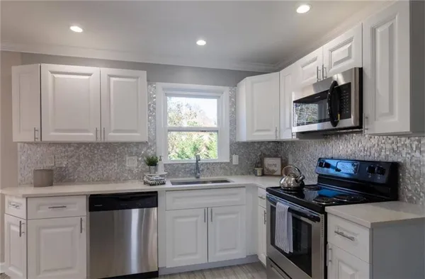 a kitchen with stainless steel appliances granite countertop white cabinets granite counter tops and a window