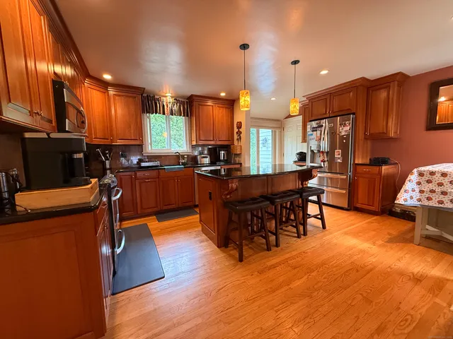 a kitchen with stainless steel appliances kitchen island granite countertop a table chairs and a refrigerator