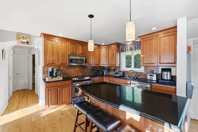 a kitchen with stainless steel appliances a stove a sink a refrigerator a window and cabinets