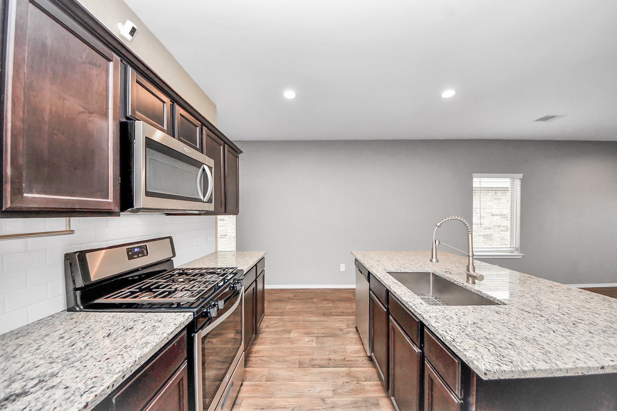 a kitchen with granite countertop stainless steel appliances sink stove microwave and cabinets