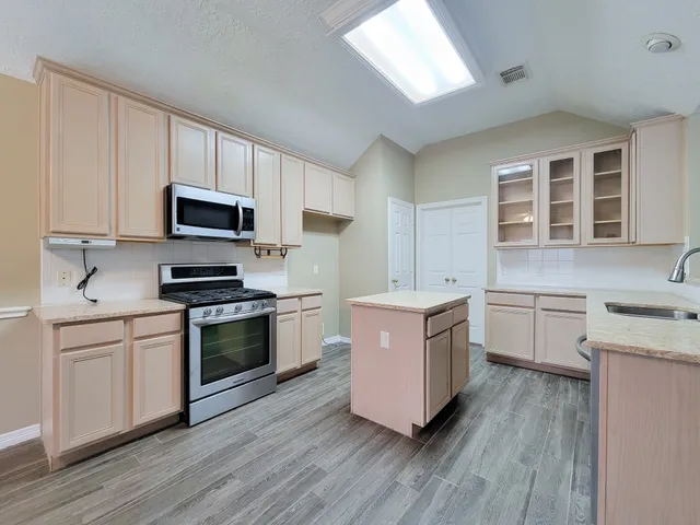 a kitchen with granite countertop stainless steel appliances a sink stove top oven and cabinets