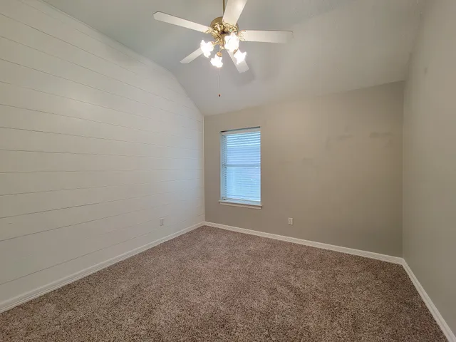 an empty room with a chandelier fan and windows