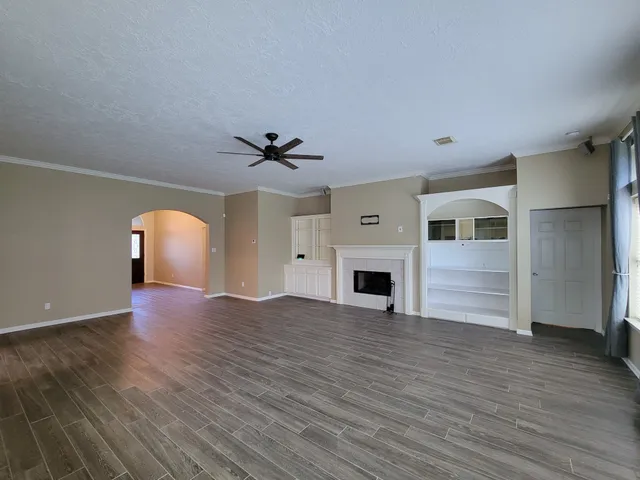 a view of an empty room with a window and wooden floor
