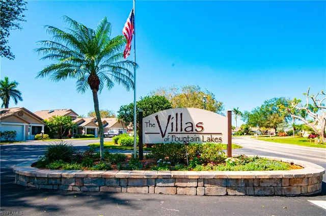 a sign that is sitting in front of a house with a garden
