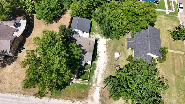 an aerial view of a house with outdoor space and trees all around