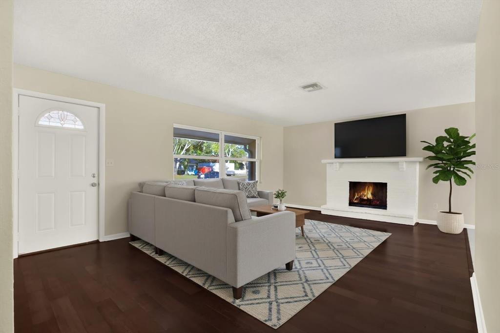 3485 Pine Street Dunedin, FL 34698 - Photo 2 of 22 a living room with furniture a flat screen tv and a fireplace