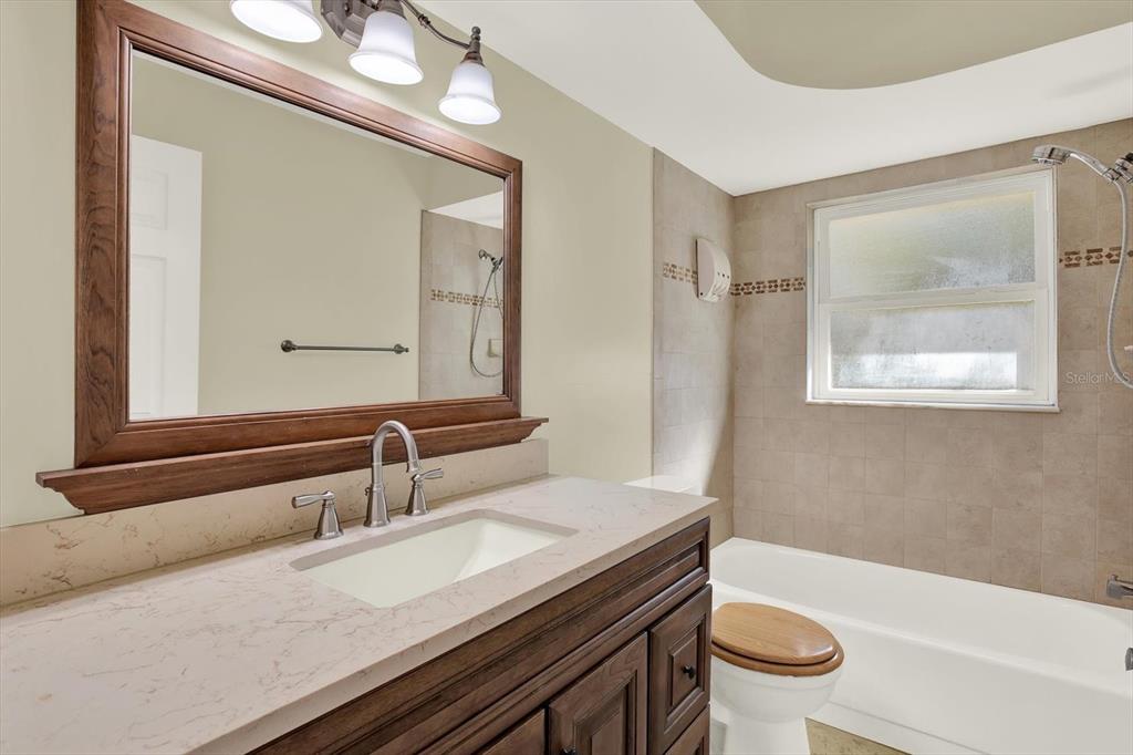 3485 Pine Street Dunedin, FL 34698 - Photo 6 of 22 a bathroom with a granite countertop sink a toilet a mirror and bathtub