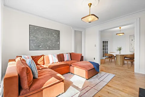 a living room with blue couches and a dining table with wooden floor