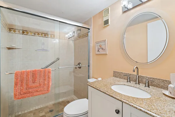 a bathroom with a granite countertop sink mirror vanity and a shower