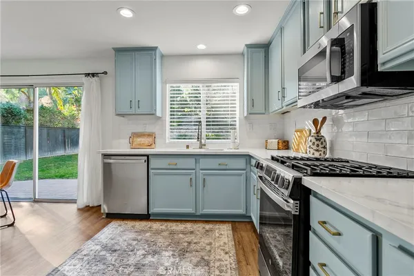 a kitchen with stainless steel appliances granite countertop a stove a sink and a microwave
