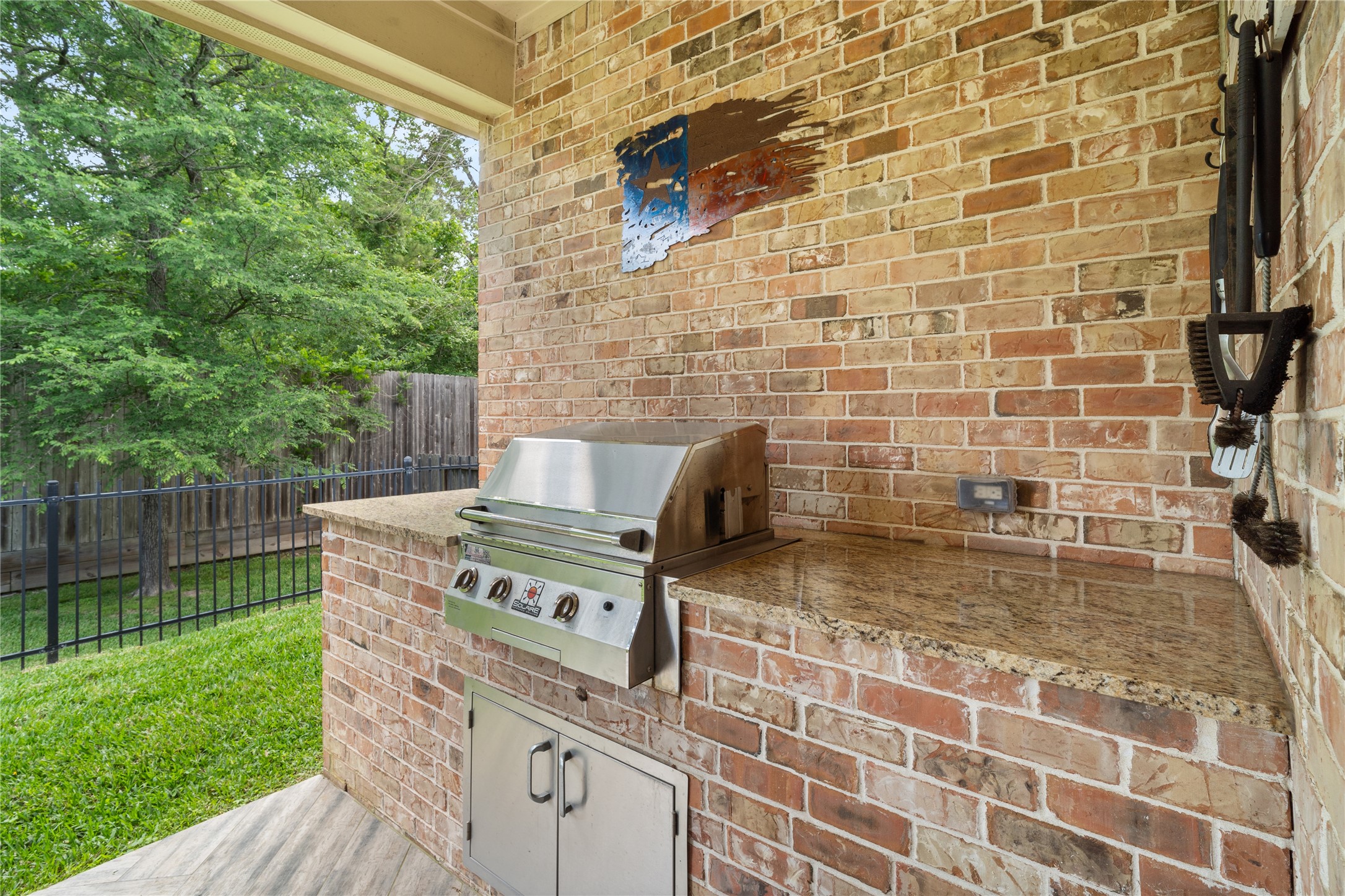 19813 Cullen Ridge Drive Porter, TX 77365 - Photo 41 of 44 This inviting outdoor kitchen features a sleek grill set against a charming brick backdrop, perfect for alfresco dining and entertaining in a serene backyard setting.