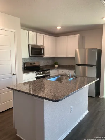 a kitchen with stainless steel appliances granite countertop a sink a microwave a refrigerator and white cabinets