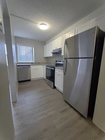 a kitchen with refrigerator and white cabinets