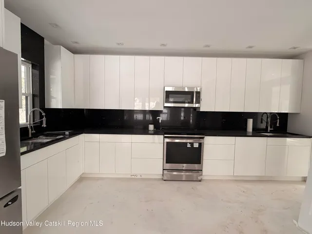 a kitchen with stainless steel appliances a stove a sink and a white cabinets