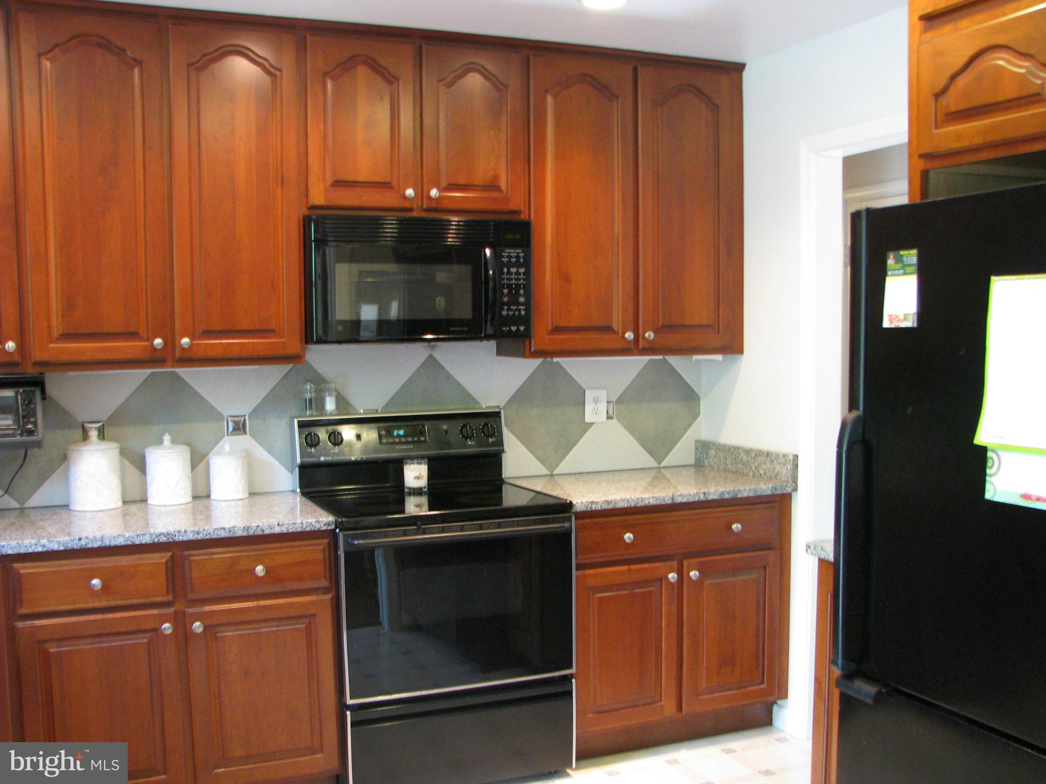 4207 Jackson Mill Road Haymarket, VA 20169 - Photo 6 of 30 a kitchen with granite countertop wood cabinets and stainless steel appliances