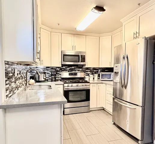 a kitchen with stainless steel appliances a refrigerator sink and microwave