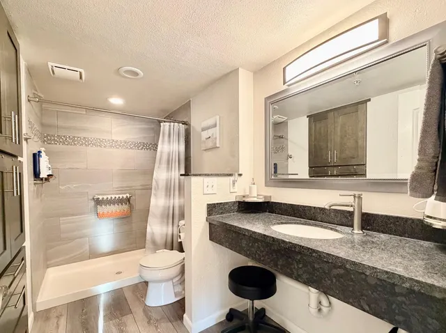 a bathroom with a granite countertop toilet a sink and a mirror