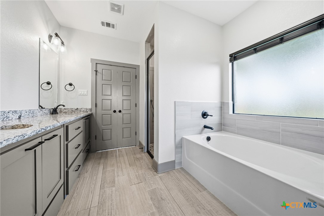 2892 Beulah Boulevard Belton, TX 76513 - Photo 15 of 47 a spacious bathroom with a double vanity sink a mirror and a bathtub
